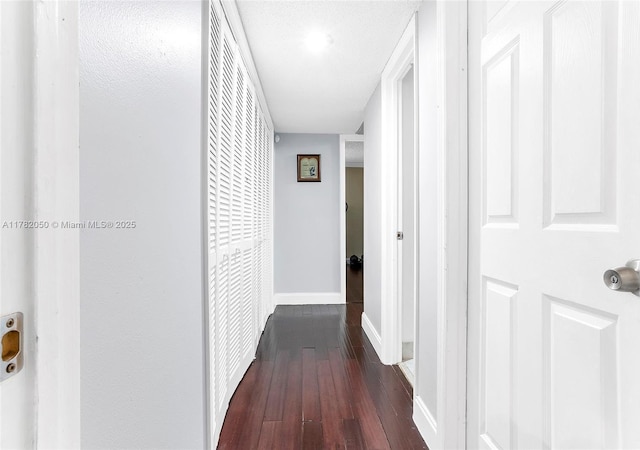 hallway with dark wood-type flooring and baseboards