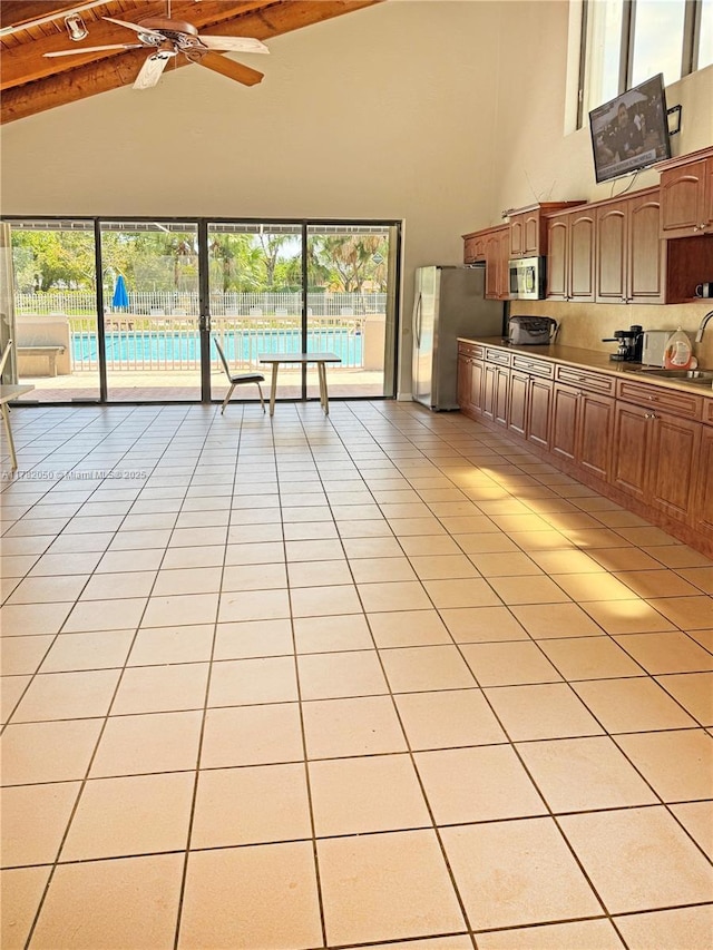 kitchen featuring high vaulted ceiling, beamed ceiling, a ceiling fan, appliances with stainless steel finishes, and backsplash