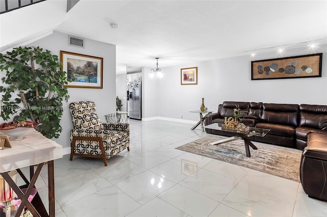 living area with visible vents, baseboards, marble finish floor, and an inviting chandelier