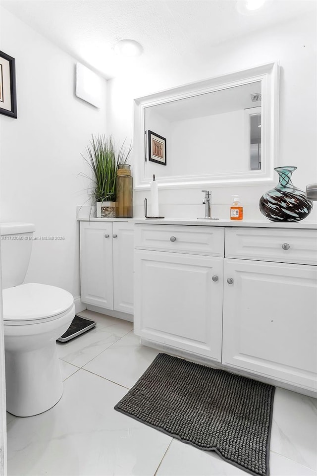half bathroom featuring visible vents, toilet, marble finish floor, and vanity