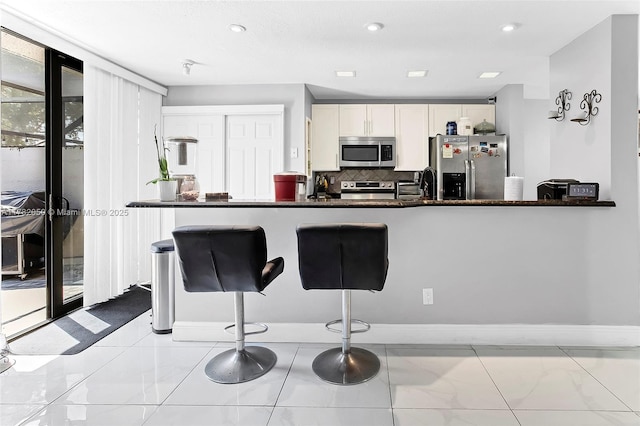 kitchen featuring backsplash, white cabinetry, marble finish floor, and stainless steel appliances