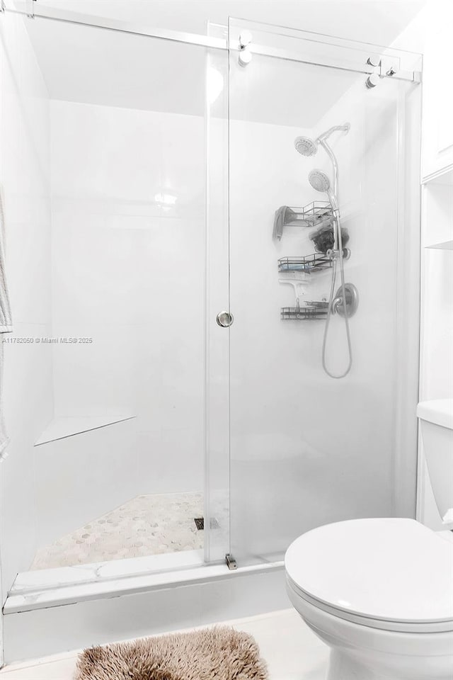 bathroom with a shower stall and toilet