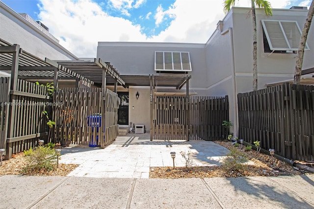 view of front of home featuring a pergola, fence, a gate, and stucco siding