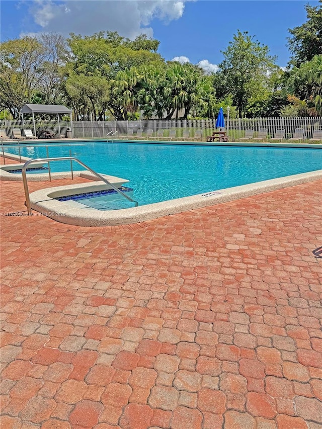 community pool with a patio area and fence