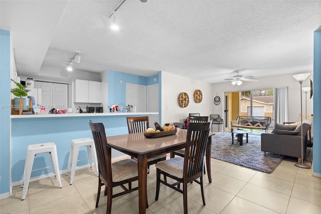 dining room with light tile patterned floors, track lighting, and ceiling fan