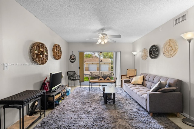living room with a ceiling fan, visible vents, and a textured ceiling