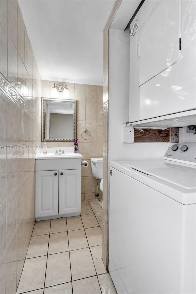 300 NW 107th Ave Unit 201, Miami, FL 33172 - half bathroom featuring vanity, tile patterned flooring, toilet, tile walls, and stacked washing maching and dryer
