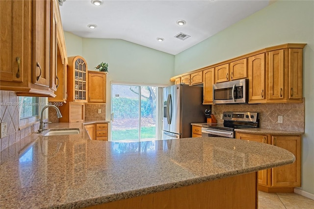 kitchen featuring appliances with stainless steel finishes, light stone countertops, visible vents, lofted ceiling, and a sink