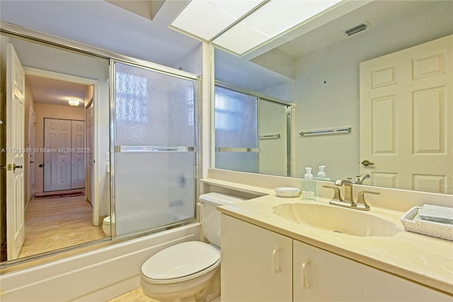 bathroom featuring toilet, vanity, visible vents, and bath / shower combo with glass door