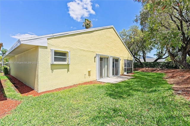 rear view of property featuring stucco siding and a lawn