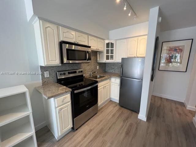 4228 N Ocean Dr Unit 17, Lauderdale By The Sea, FL 33308 - kitchen with a sink, light stone counters, light wood finished floors, backsplash, and appliances with stainless steel finishes