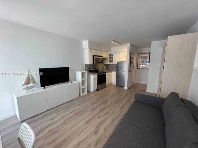 4228 N Ocean Dr Unit 17, Lauderdale By The Sea, FL 33308 - living room featuring rail lighting, light wood-style floors, and baseboards