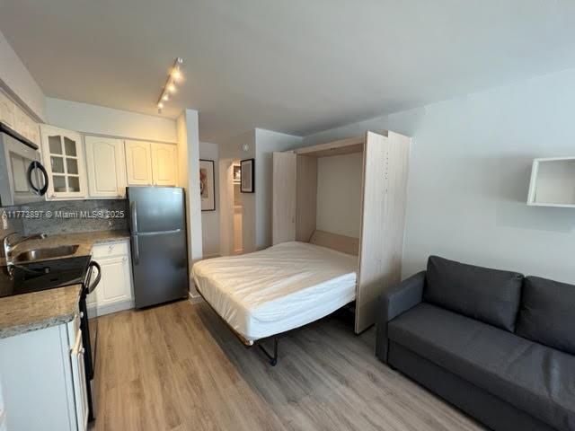 4228 N Ocean Dr Unit 17, Lauderdale By The Sea, FL 33308 - bedroom with freestanding refrigerator, light wood-type flooring, and a sink