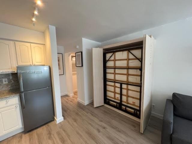 4228 N Ocean Dr Unit 17, Lauderdale By The Sea, FL 33308 - interior space featuring light wood-style flooring, freestanding refrigerator, white cabinetry, baseboards, and light stone counters