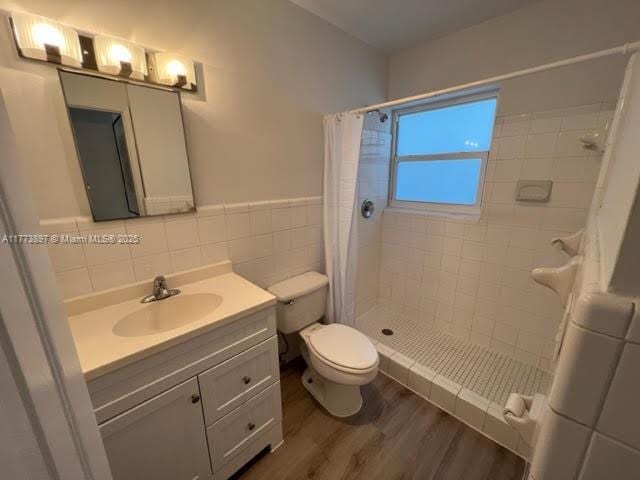 4228 N Ocean Dr Unit 17, Lauderdale By The Sea, FL 33308 - full bathroom featuring toilet, wood finished floors, tiled shower, tile walls, and vanity
