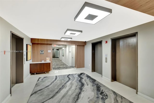 corridor with elevator and light tile patterned floors