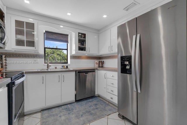 kitchen featuring visible vents, a sink, white cabinetry, stainless steel appliances, and light tile patterned flooring