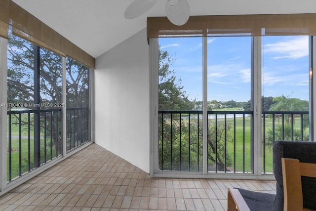 unfurnished sunroom with lofted ceiling, a ceiling fan, and tile patterned flooring