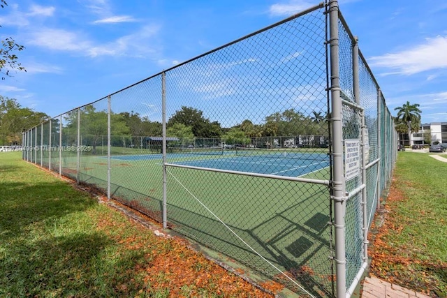 view of tennis court featuring a yard and fence