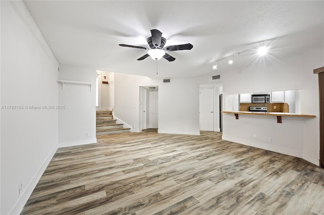 9239 W Sunrise Blvd, Plantation, FL 33322 - unfurnished living room featuring ceiling fan, rail lighting, visible vents, stairway, and light wood finished floors