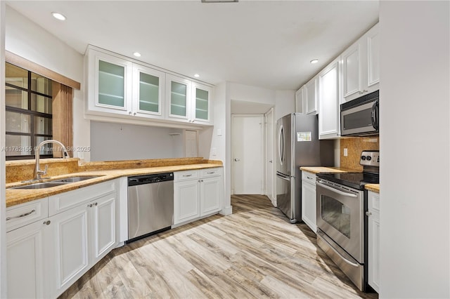 9239 W Sunrise Blvd, Plantation, FL 33322 - kitchen featuring light wood-style floors, glass insert cabinets, white cabinetry, appliances with stainless steel finishes, and a sink
