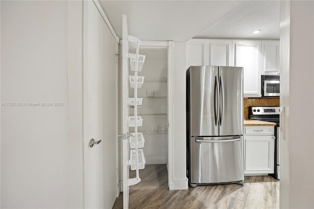 9239 W Sunrise Blvd, Plantation, FL 33322 - kitchen featuring stainless steel appliances, light wood-type flooring, baseboards, and white cabinetry