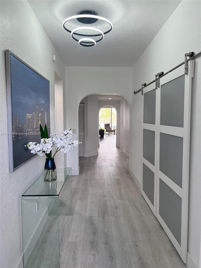 10770 NW 66th St Unit 203, Doral, FL 33178 - hall featuring arched walkways, a barn door, wood finished floors, a textured ceiling, and a textured wall
