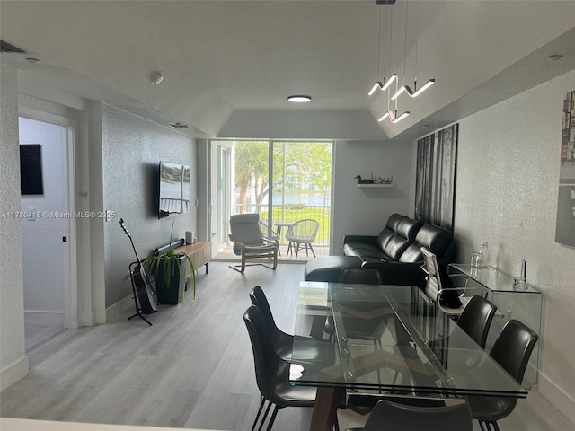 dining area featuring baseboards, wood finished floors, and a textured wall
