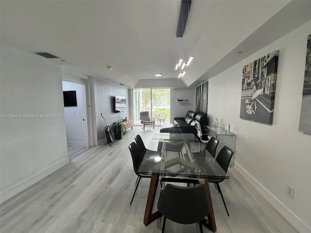 dining room with light wood-type flooring, a textured wall, baseboards, and visible vents