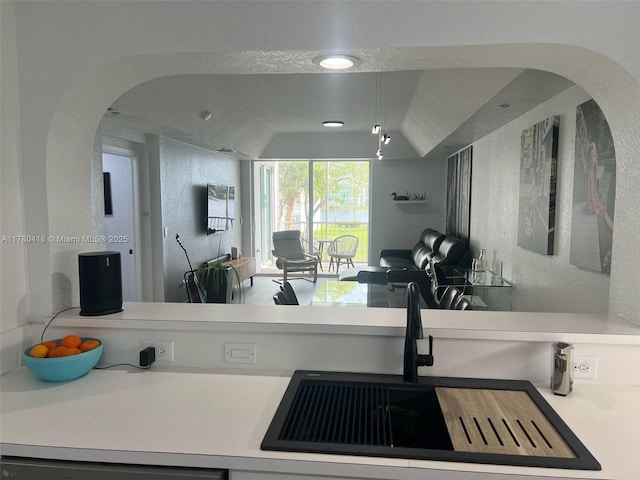 kitchen featuring open floor plan, arched walkways, a sink, and light countertops