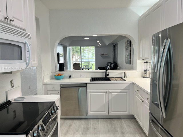 10770 NW 66th St Unit 203, Doral, FL 33178 - kitchen featuring stainless steel appliances, a sink, arched walkways, and white cabinets