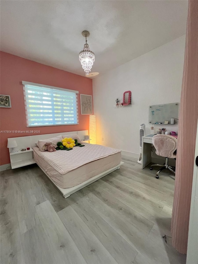 bedroom featuring baseboards, an inviting chandelier, and wood finished floors