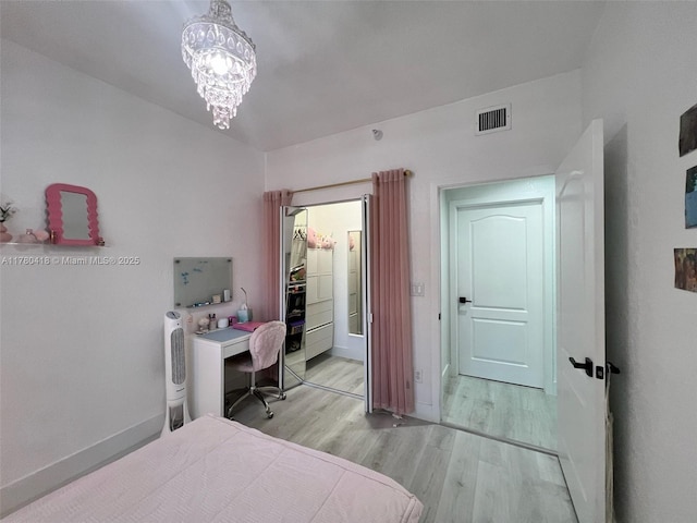 bedroom featuring light wood-style flooring, baseboards, visible vents, and a notable chandelier