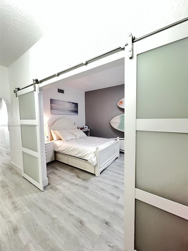 10770 NW 66th St Unit 203, Doral, FL 33178 - bedroom with a barn door, light wood-style floors, and a textured ceiling