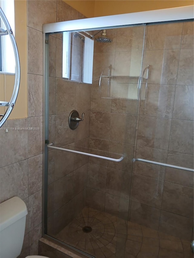bathroom featuring toilet and a stall shower