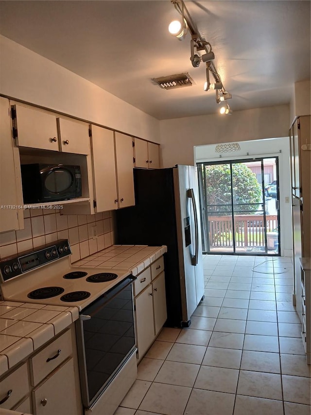 kitchen with black microwave, white cabinetry, visible vents, electric stove, and tile countertops