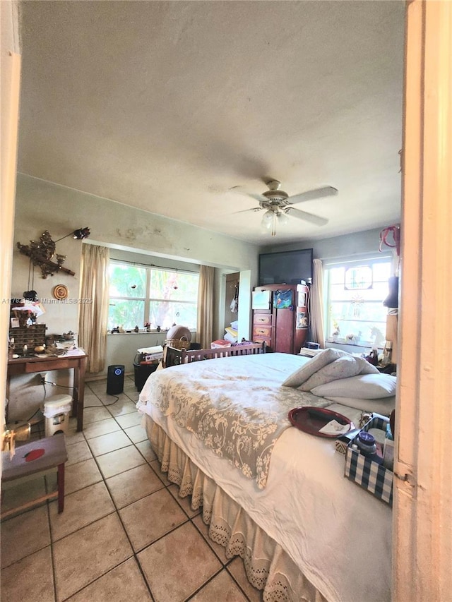 tiled bedroom featuring a textured ceiling, multiple windows, and ceiling fan