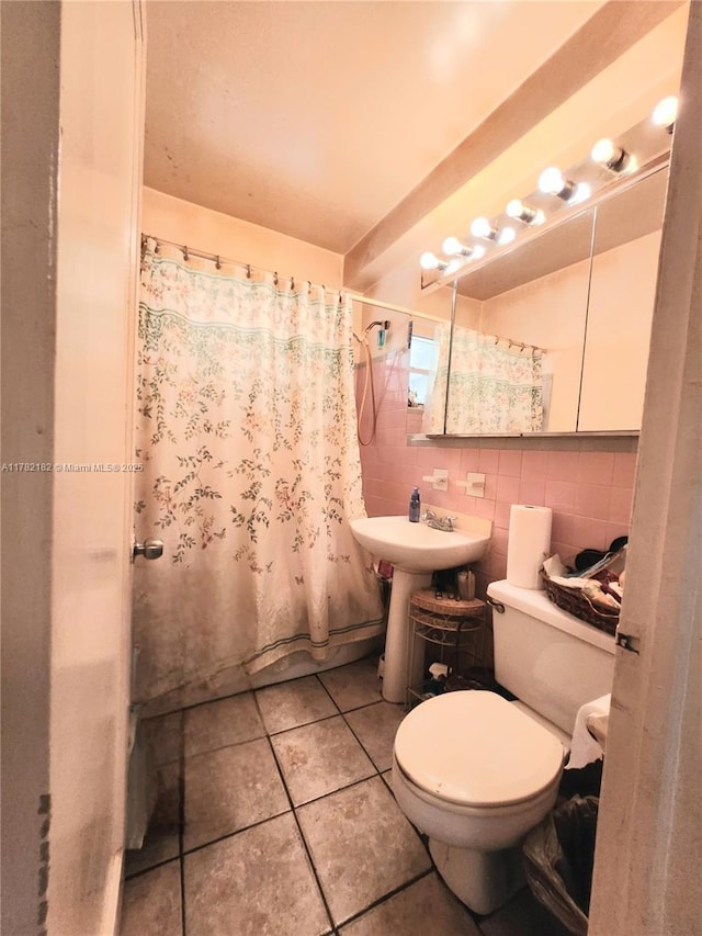 bathroom with a sink, toilet, shower / bath combination with curtain, tile walls, and tile patterned flooring