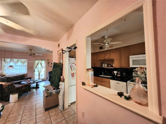 kitchen featuring light tile patterned flooring, white appliances, a ceiling fan, and a sink