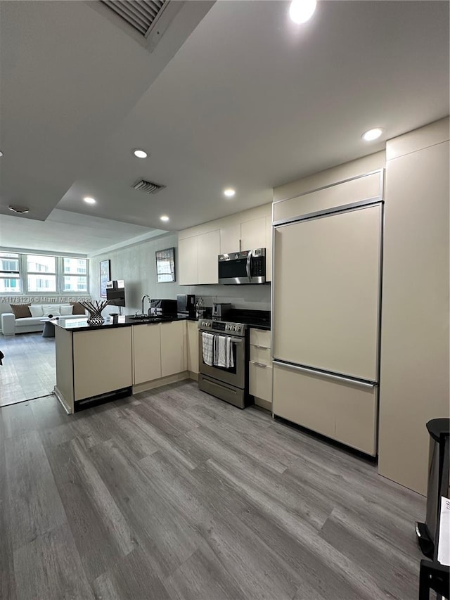 kitchen featuring visible vents, open floor plan, dark countertops, wood finished floors, and stainless steel appliances