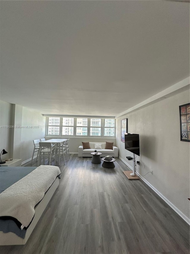 living area with baseboards, wood finished floors, and a healthy amount of sunlight