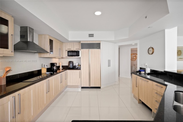 kitchen featuring wall chimney range hood, a tray ceiling, black appliances, and light brown cabinets
