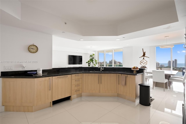kitchen featuring a sink, light tile patterned floors, open floor plan, light brown cabinets, and recessed lighting