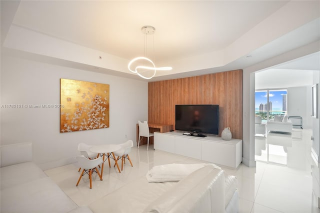 living room with a tray ceiling, a chandelier, and light tile patterned floors