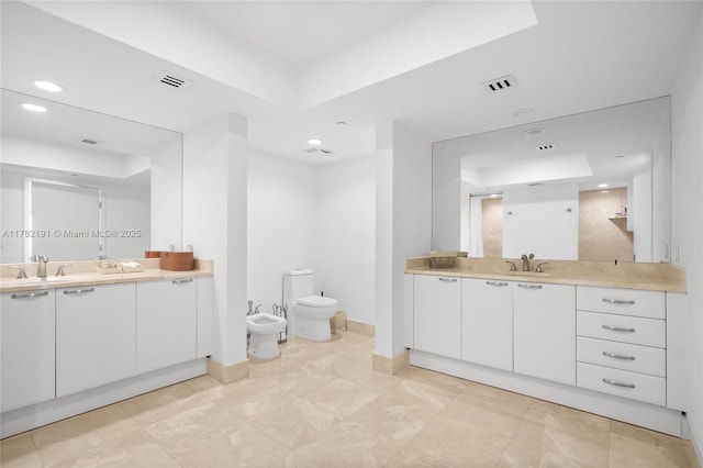 full bath featuring visible vents, toilet, two vanities, a sink, and a bidet
