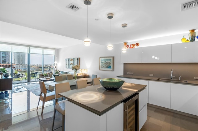 68 SE 6th St Unit 810, Miami, FL 33131 - kitchen featuring wine cooler, white cabinetry, dark countertops, a center island, and pendant lighting