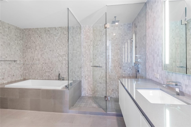 68 SE 6th St Unit 810, Miami, FL 33131 - bathroom with tile walls, vanity, a stall shower, a garden tub, and tile patterned floors