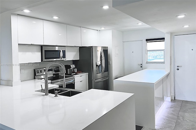 kitchen with a peninsula, light countertops, white cabinets, modern cabinets, and appliances with stainless steel finishes