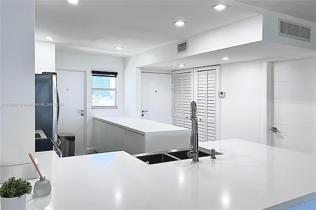 kitchen with a sink, visible vents, freestanding refrigerator, and recessed lighting