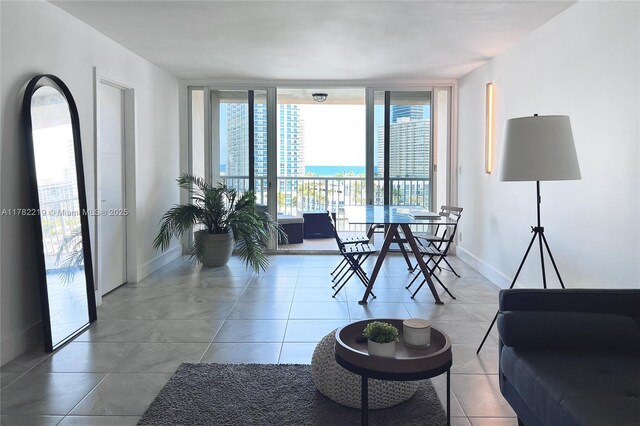 121 Golden Isles Dr Unit 803, Hallandale Beach, FL 33009 - tiled living room featuring a wall of windows and baseboards